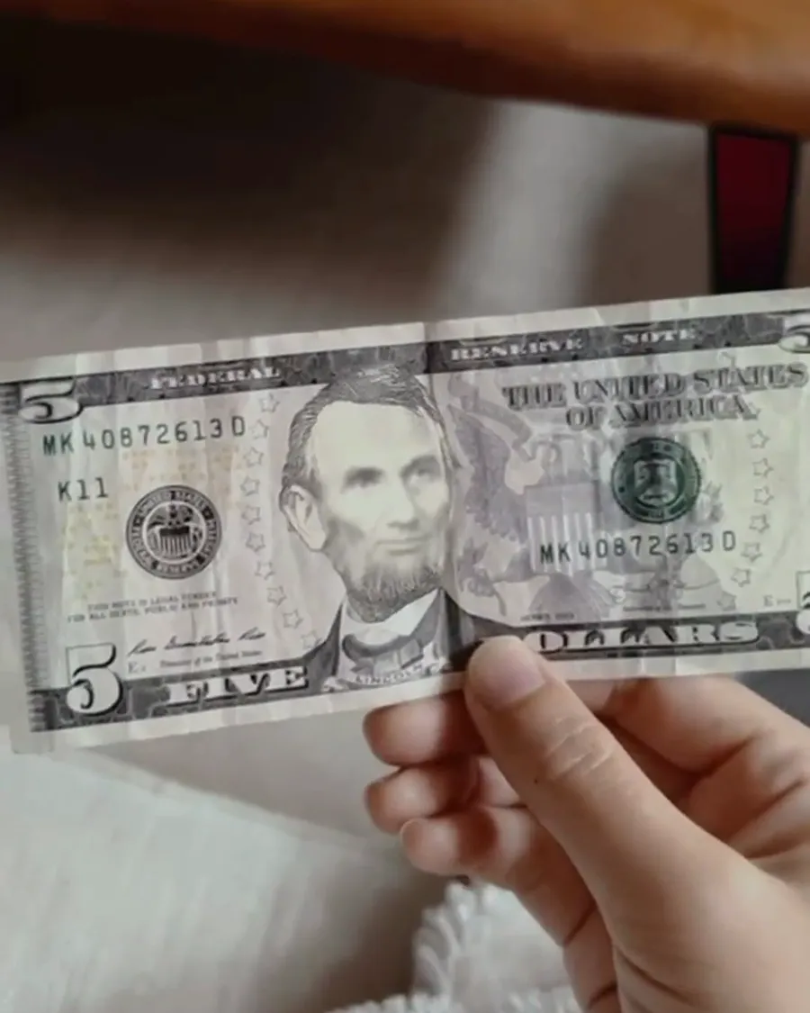 A hand holding a US five dollar bill up to the phone camera, with Lincoln's portrait used as the image-tracking target